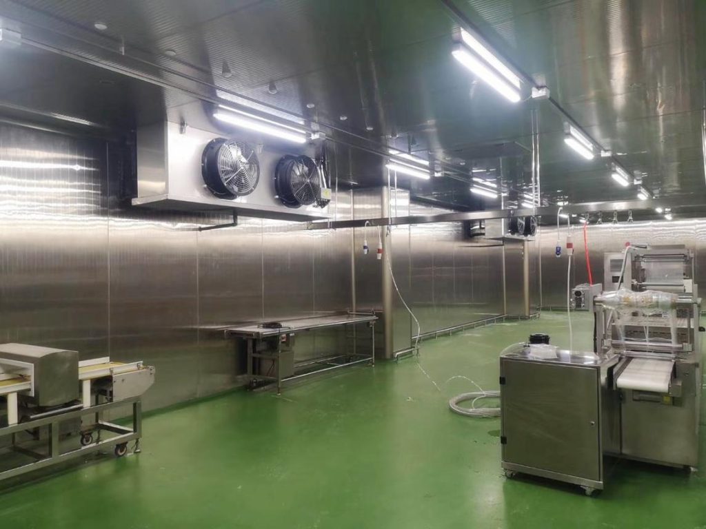 Chiller room with ceiling-mounted air coolers and stainless steel processing equipment for food preparation under controlled temperature