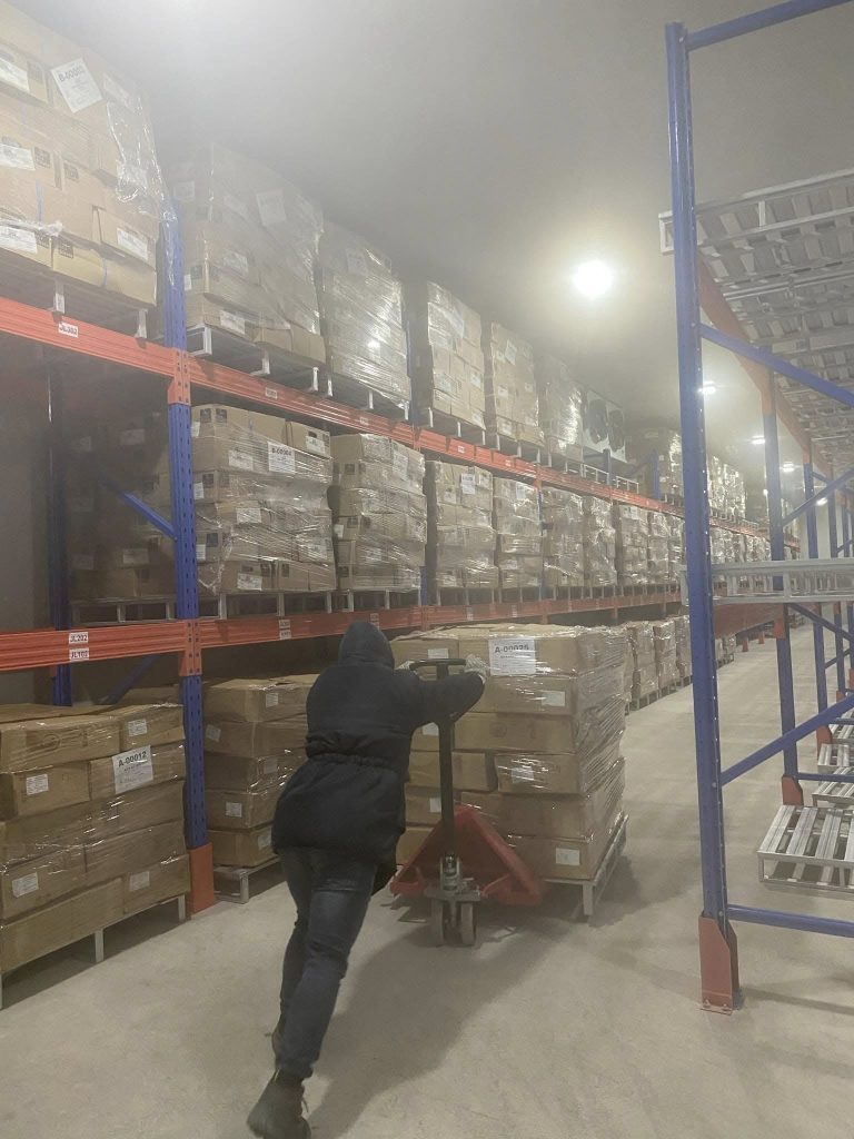 Large freezer room cold storage warehouse with high-density racking system and pallet jack operations at -18°C to -25°C