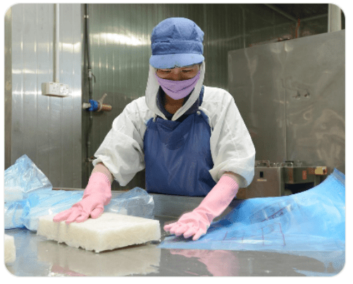 Food processing worker handling fresh products in a hygienic cold processing room with temperature-controlled environment